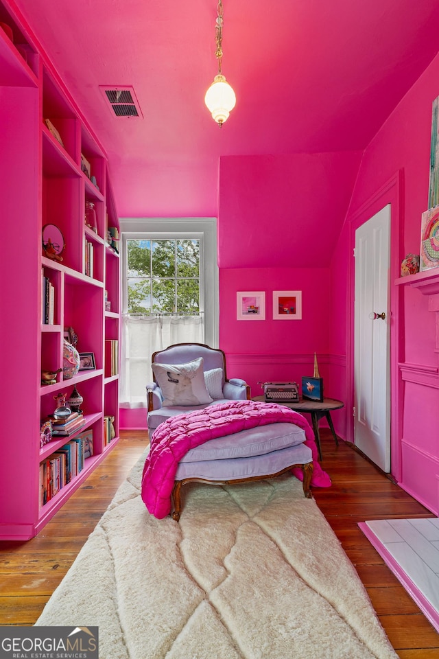 bedroom with vaulted ceiling, wood finished floors, and visible vents