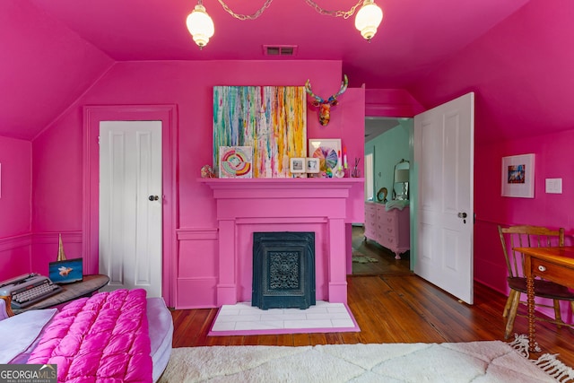 living area featuring wood finished floors, lofted ceiling, visible vents, and a fireplace