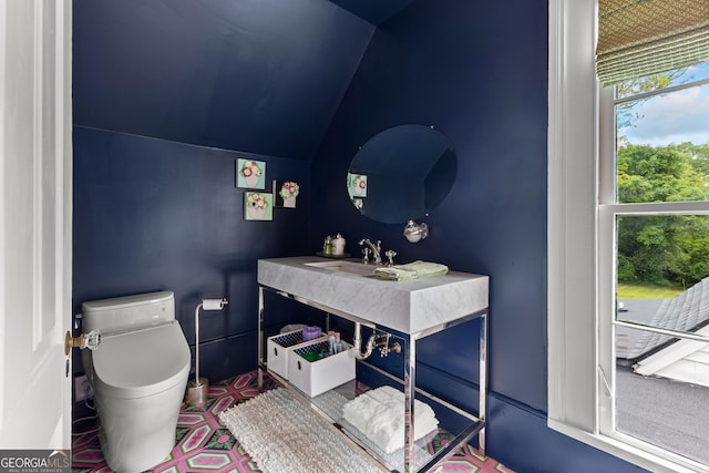 half bathroom featuring vanity, vaulted ceiling, and toilet