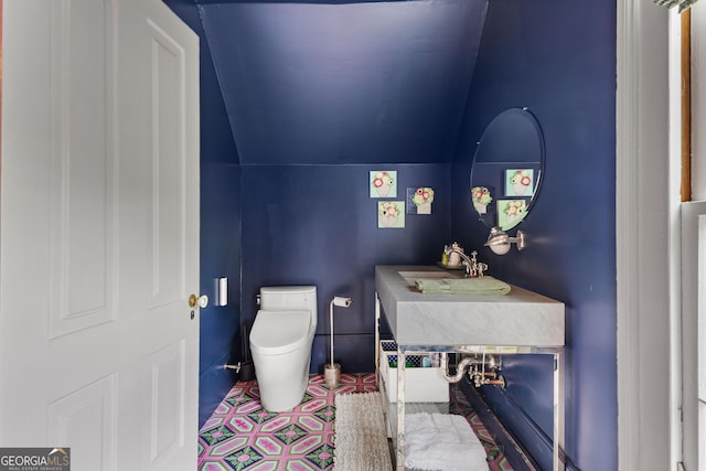 half bathroom featuring vaulted ceiling and toilet