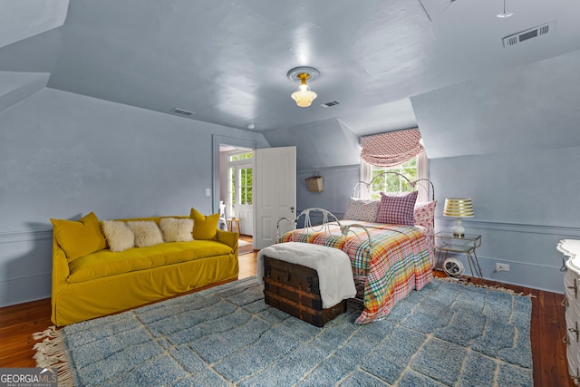 bedroom featuring multiple windows, lofted ceiling, wood finished floors, and visible vents