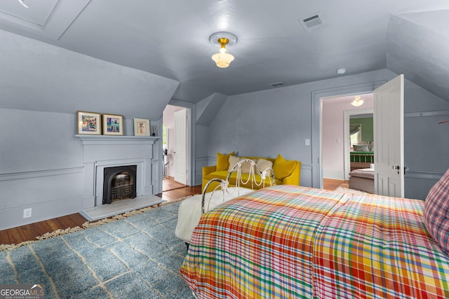 bedroom with visible vents, wood finished floors, and vaulted ceiling