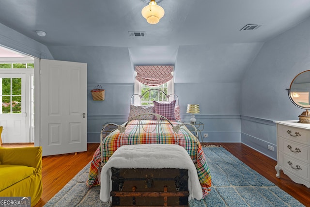 bedroom with visible vents, wood finished floors, and lofted ceiling