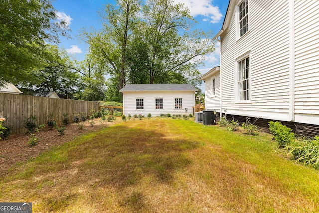 view of yard featuring fence, an outbuilding, and cooling unit