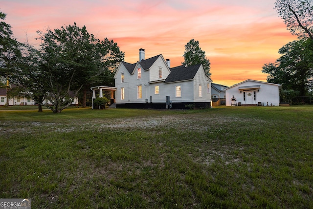 exterior space with a yard, a chimney, and a shingled roof