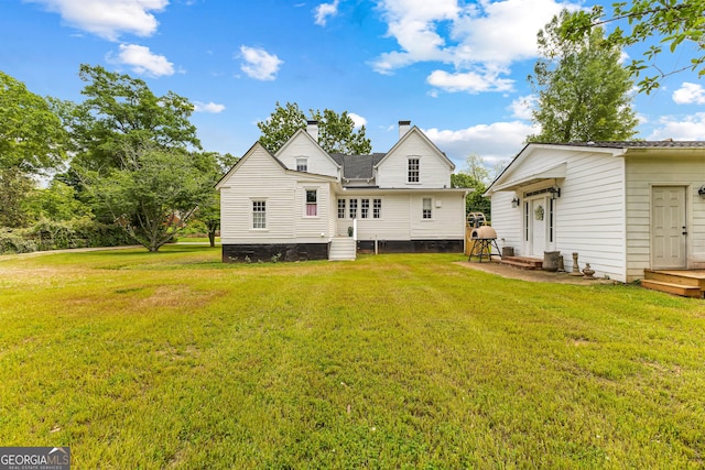 rear view of house with a lawn, a chimney, and entry steps