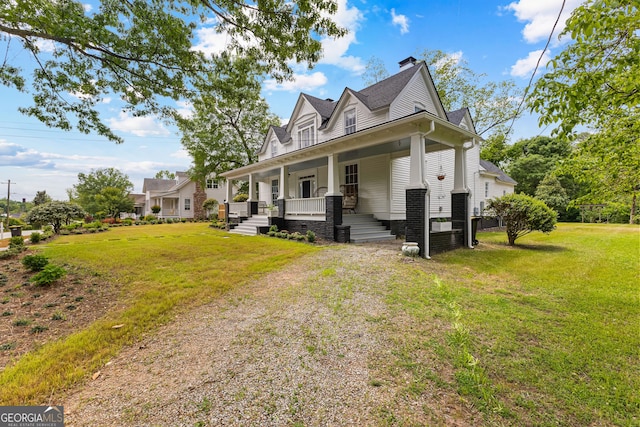 view of front facade featuring covered porch, a chimney, and a front yard