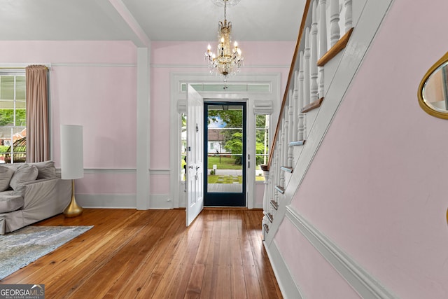 entrance foyer with baseboards, a chandelier, stairway, and hardwood / wood-style floors