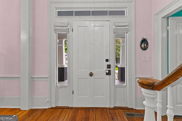 foyer featuring baseboards, wood finished floors, and visible vents