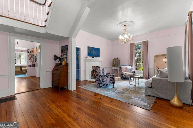 living room featuring visible vents, a notable chandelier, a wealth of natural light, and hardwood / wood-style flooring