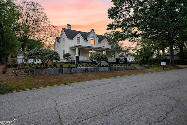 country-style home with a porch and a chimney