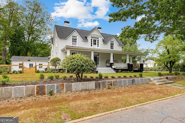 view of front of home featuring covered porch, a chimney, and a front lawn