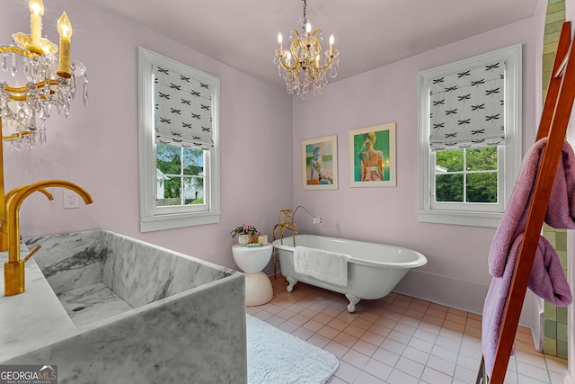 full bath with tile patterned flooring, a sink, a notable chandelier, and a soaking tub