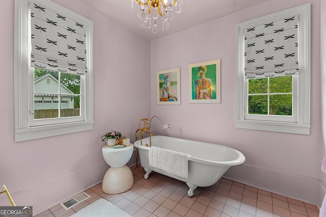 bathroom featuring a freestanding bath, plenty of natural light, a chandelier, and visible vents