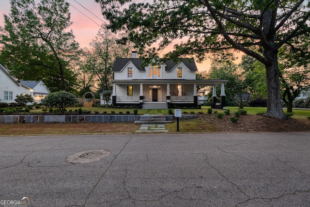 farmhouse inspired home with a porch and a chimney