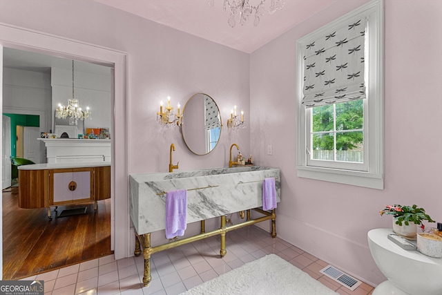 bathroom with an inviting chandelier, vanity, toilet, tile patterned floors, and visible vents