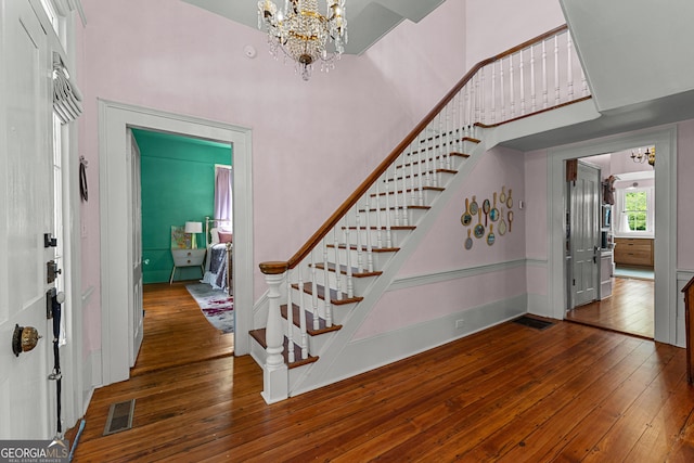 foyer with stairs, a high ceiling, a chandelier, and hardwood / wood-style flooring