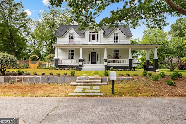 view of front facade featuring a shingled roof, a porch, and a front yard