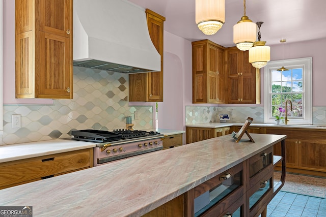 kitchen with custom range hood, a sink, brown cabinetry, and backsplash