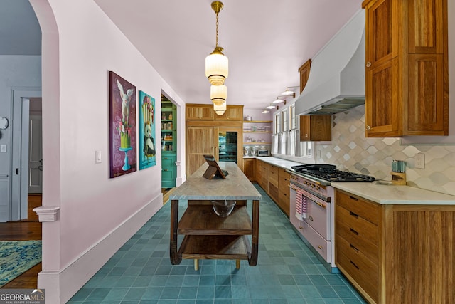 kitchen with light countertops, decorative backsplash, brown cabinetry, and custom exhaust hood