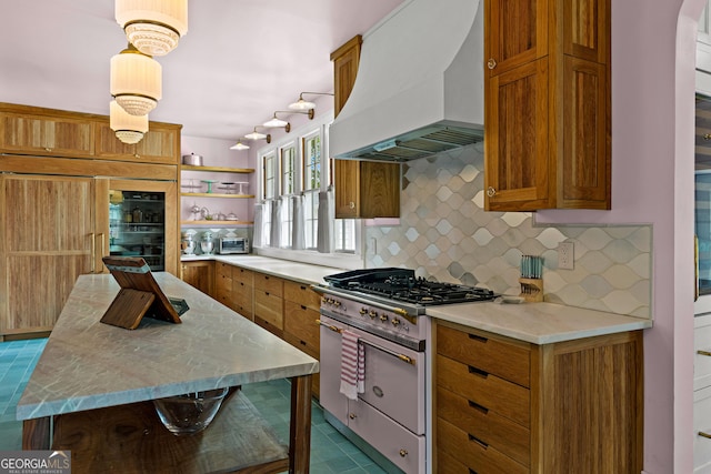 kitchen featuring open shelves, custom exhaust hood, brown cabinets, range with gas cooktop, and backsplash