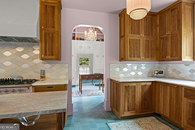 kitchen featuring light countertops, exhaust hood, stainless steel gas stovetop, and brown cabinets