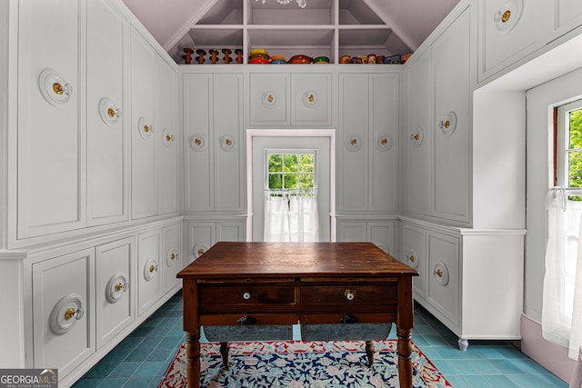 home office with dark tile patterned floors and vaulted ceiling
