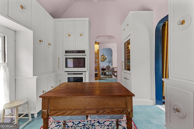 home office with arched walkways and vaulted ceiling