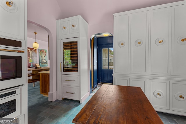 interior space with arched walkways, dark tile patterned floors, and beverage cooler