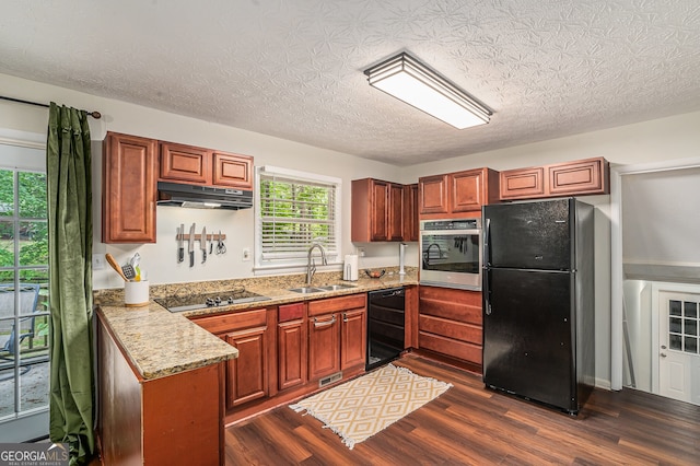 2623 Riggs Dr, Atlanta, GA 30344 - kitchen featuring light stone countertops, under cabinet range hood, a sink, dark wood finished floors, and black appliances