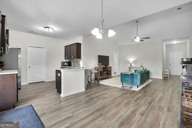 481 Akins Ranch Rd NE, Ludowici, GA 31316 - kitchen with visible vents, dark brown cabinets, ceiling fan with notable chandelier, open floor plan, and light wood-style flooring
