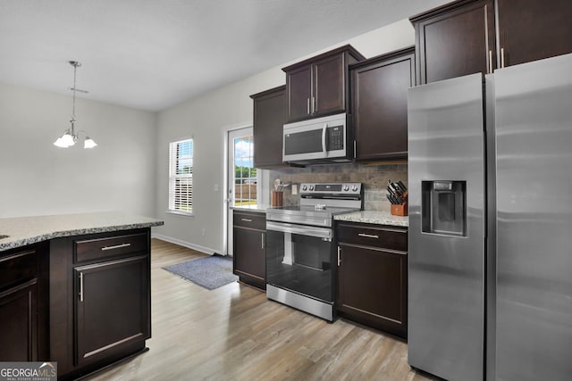 481 Akins Ranch Rd NE, Ludowici, GA 31316 - kitchen with dark brown cabinets, a notable chandelier, stainless steel appliances, light wood-type flooring, and tasteful backsplash