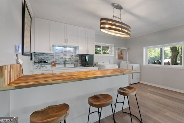 175 Mayo Rd, Covington, GA 30014 - kitchen featuring washing machine and clothes dryer, white cabinets, a sink, plenty of natural light, and butcher block counters