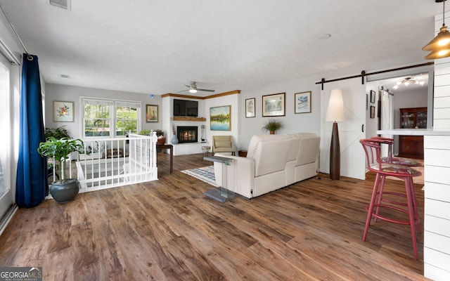 175 Mayo Rd, Covington, GA 30014 - living room with ceiling fan, a warm lit fireplace, a barn door, and wood finished floors