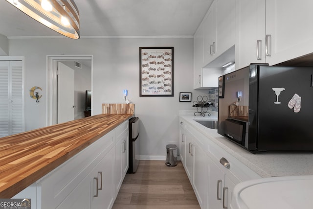 175 Mayo Rd, Covington, GA 30014 - kitchen with butcher block countertops, light wood-style flooring, crown molding, and white cabinets