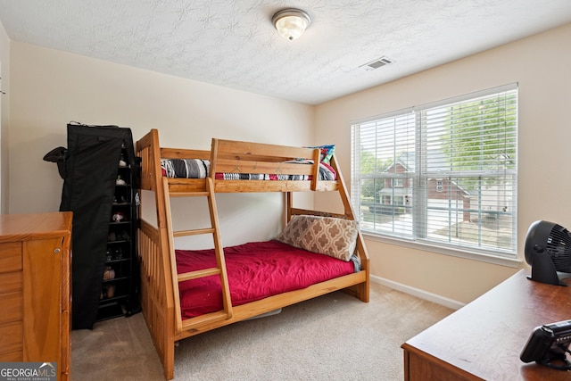 carpeted bedroom with baseboards, a textured ceiling, and visible vents