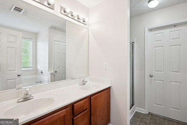 bathroom featuring a sink, double vanity, a bath, and visible vents