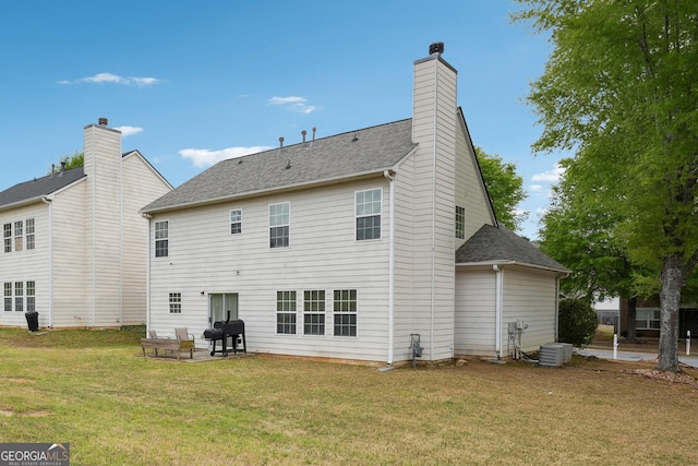 rear view of house with roof with shingles, a chimney, central air condition unit, a patio, and a yard