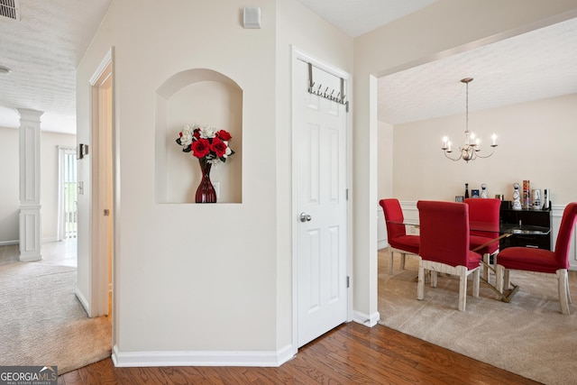 interior space featuring an inviting chandelier, a textured ceiling, baseboards, wood finished floors, and visible vents