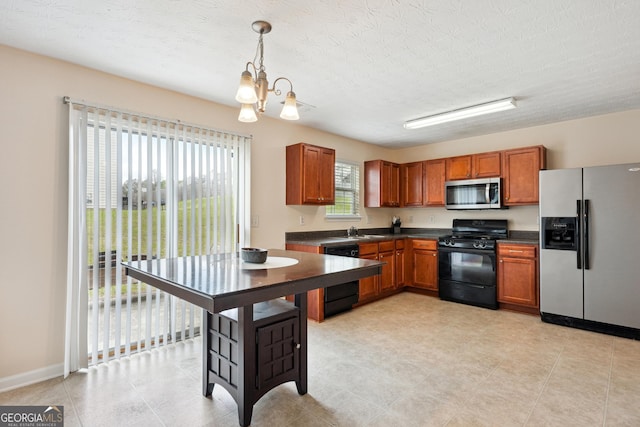 kitchen featuring brown cabinetry, dark countertops, a sink, black appliances, and a notable chandelier