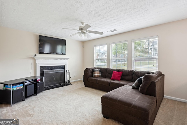 living room featuring a ceiling fan, visible vents, carpet, and a high end fireplace