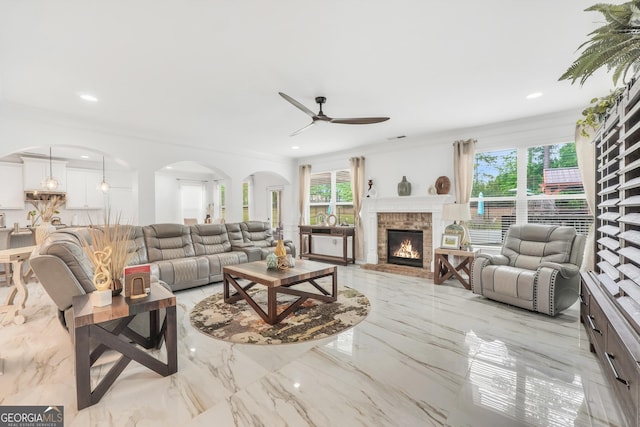 living area with marble finish floor, a brick fireplace, ceiling fan, recessed lighting, and arched walkways