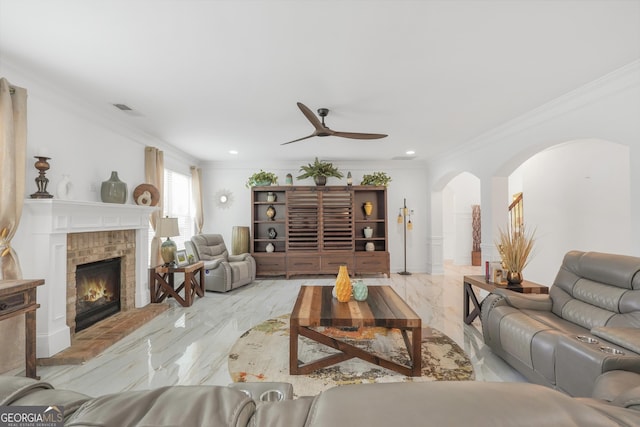 living room with ceiling fan, a fireplace, arched walkways, visible vents, and ornamental molding