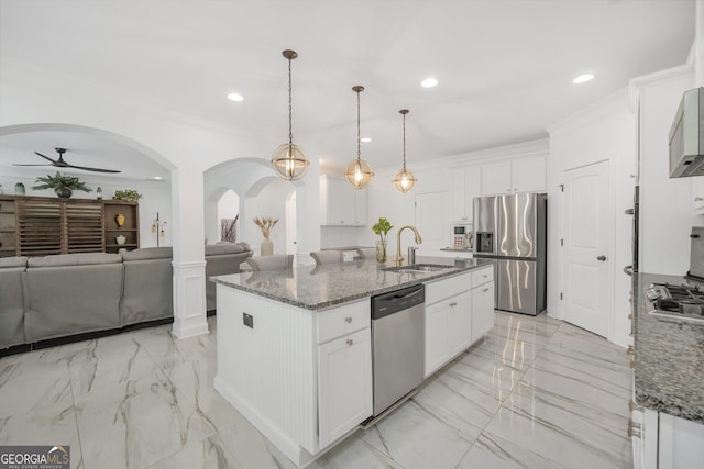 kitchen with appliances with stainless steel finishes, a sink, arched walkways, marble finish floor, and a ceiling fan