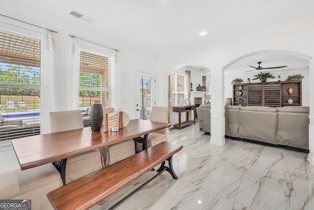 dining room with crown molding, ceiling fan, arched walkways, marble finish floor, and visible vents