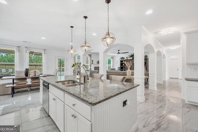 kitchen with a sink, arched walkways, ornamental molding, and an island with sink
