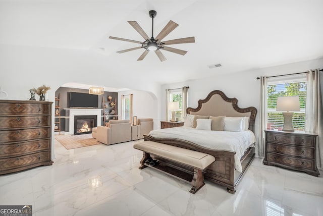 bedroom with visible vents, multiple windows, lofted ceiling, and a glass covered fireplace