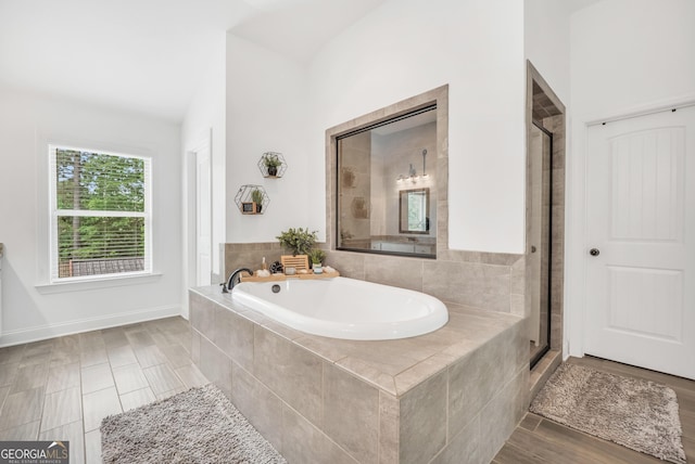 bathroom featuring baseboards, a shower stall, and a bath