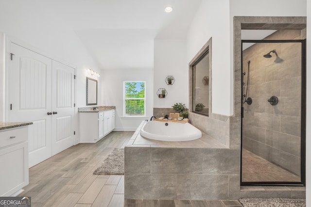 bathroom with vanity, a bath, vaulted ceiling, and a shower stall