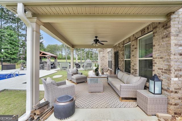 view of patio / terrace with an outdoor living space, a ceiling fan, fence, and a gazebo